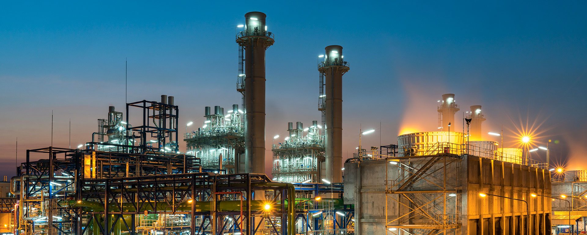 Chemical plant with tall stacks lit up at dusk